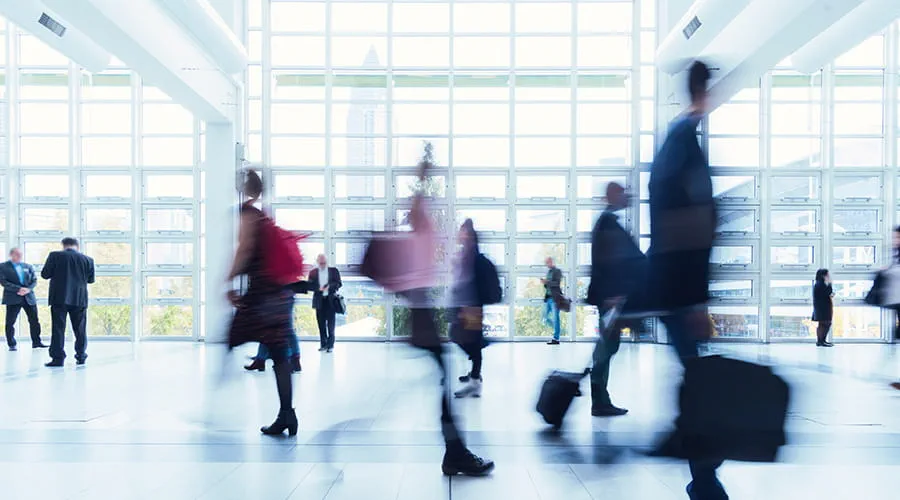 Muchas personas caminando deprisa en una estación de transporte