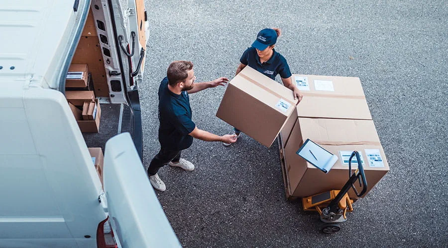 Compañeros de trabajo corriendo a cargar paquetes en una furgoneta de reparto