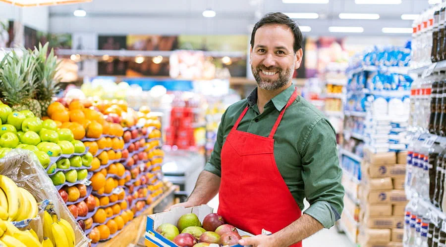 Empleado de supermercado sujetando una caja con fruta