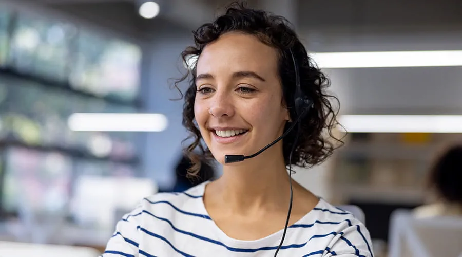 Representante de servicio al cliente usando un auricular mientras trabaja en un centro de llamadas