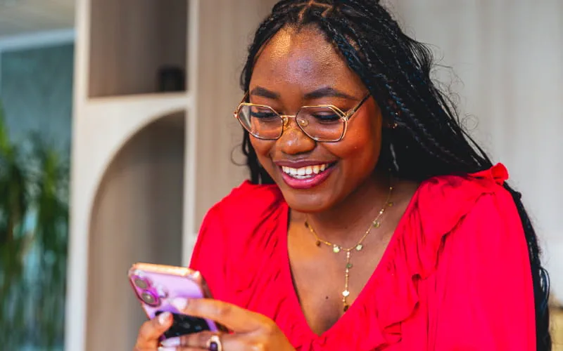 une femme souriante habillée en rouge sur son téléphone portable