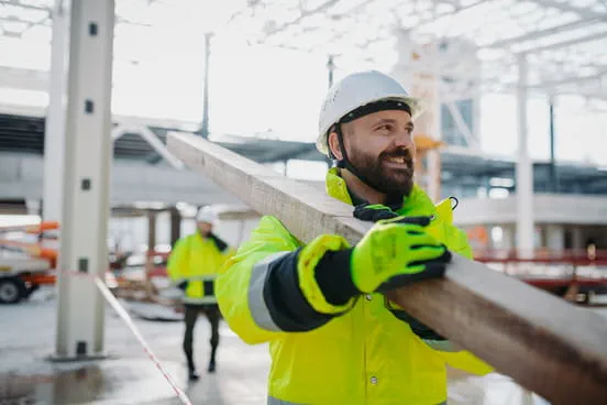 Un homme souriant portant un casque de sécurité sur un chantier de BTP.