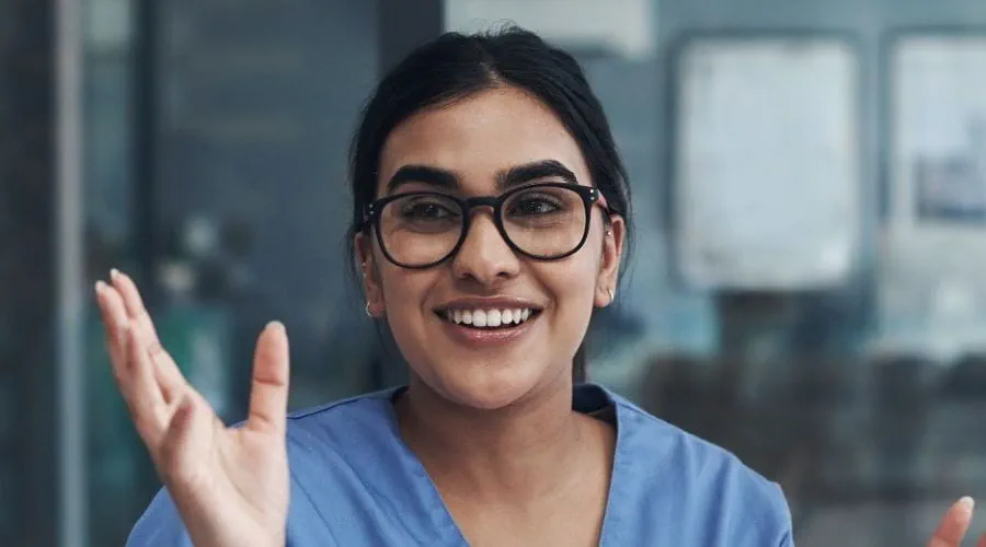 Une professionnelle de la santé souriante et portant des lunettes, parle avec deux collègues