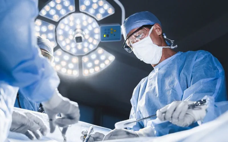 Un chirurgien portant un masque et des lunettes opère un patient