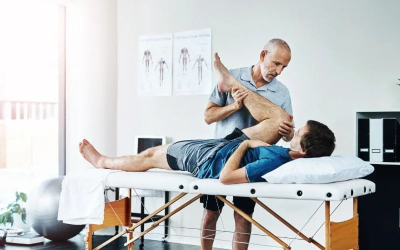 Un kinésithérapeute manipule la jambe d’un patient