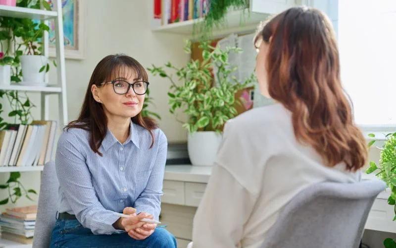 Une psychologue écoute attentivement une patiente dans un bureau lumineux