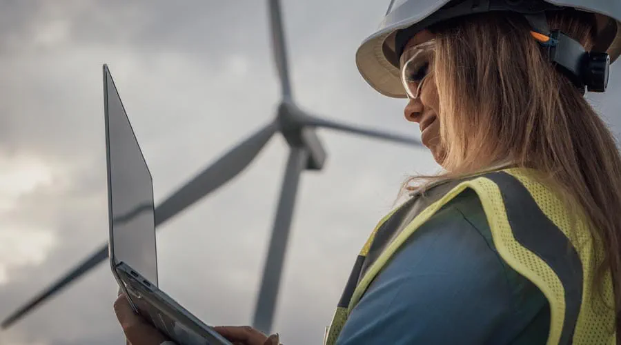 Engineer working on a laptop at a wind farm site