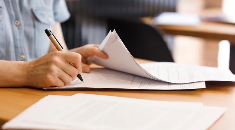 Professional signing a  document at a desk in a  modern office