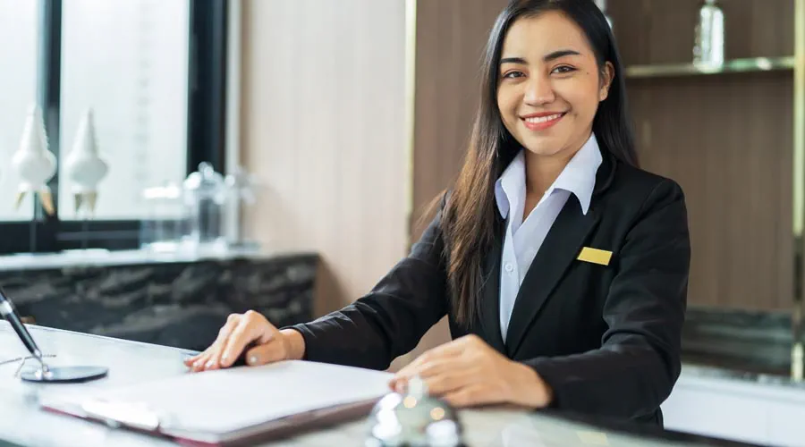 Friendly hotel receptionist welcoming guests at the front desk