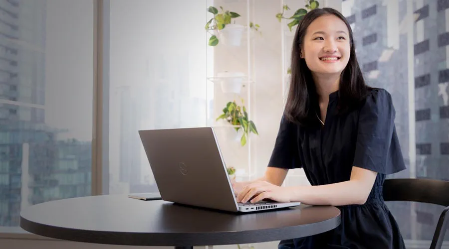 Female team member working on a laptop with a city view