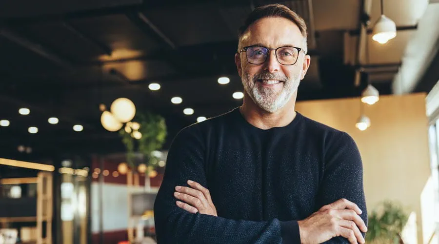 Mature businessman confidently standing in a shared office space
