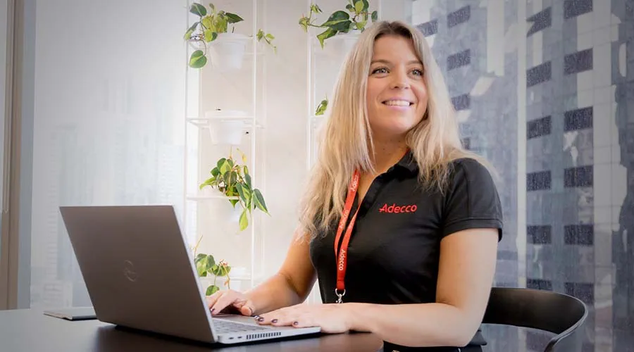 A woman working on a laptop while looking to the side.