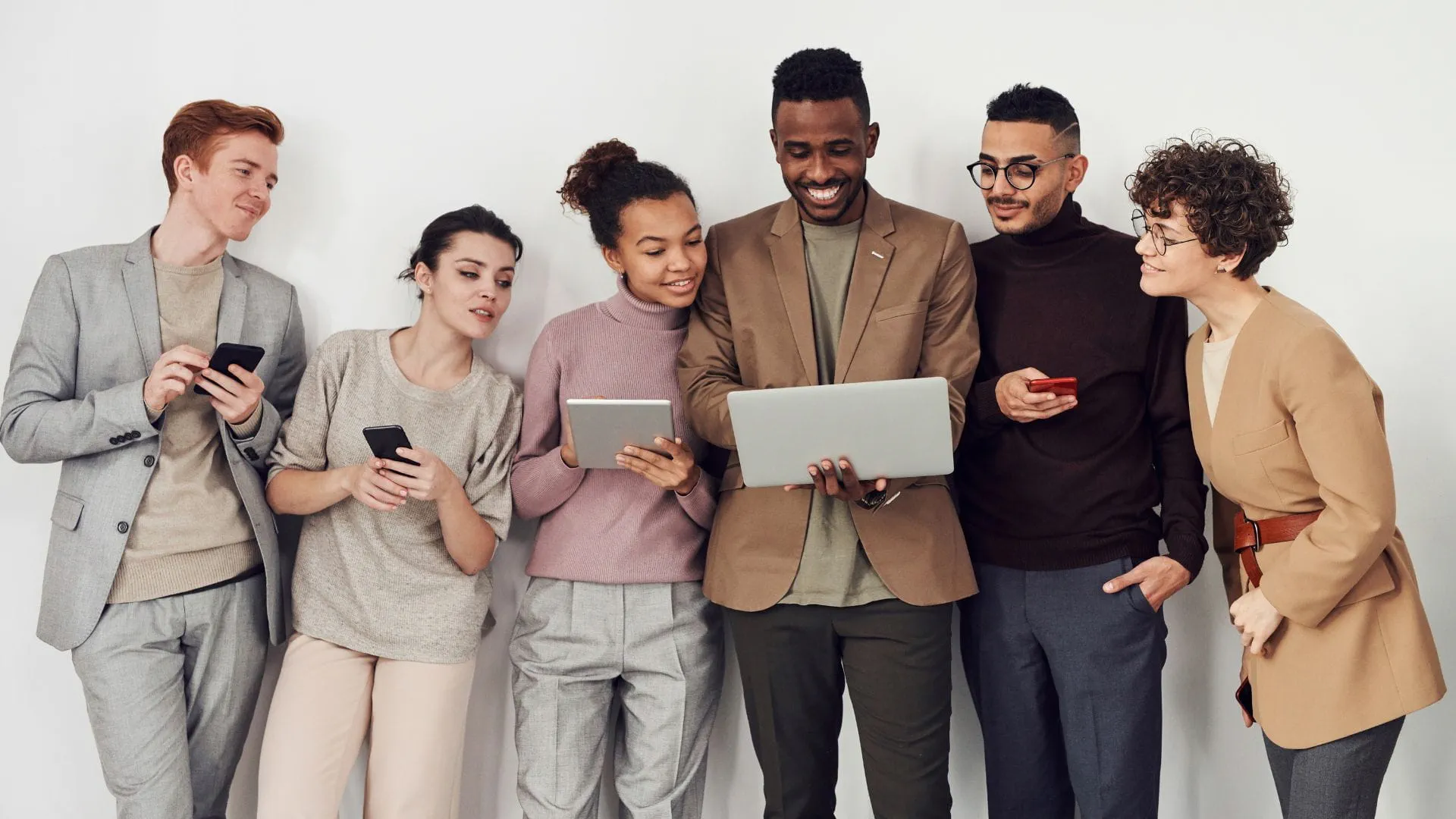 group of people standing looking at their devices and smiling