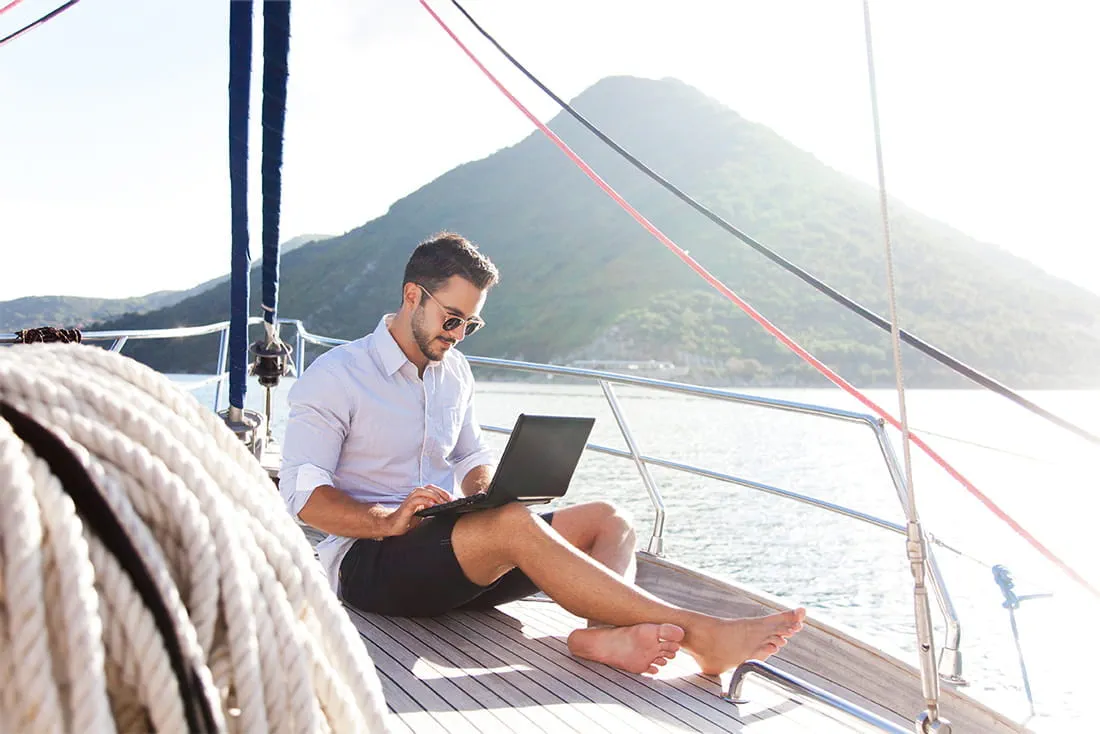 Mann mit Laptop auf einem Boot