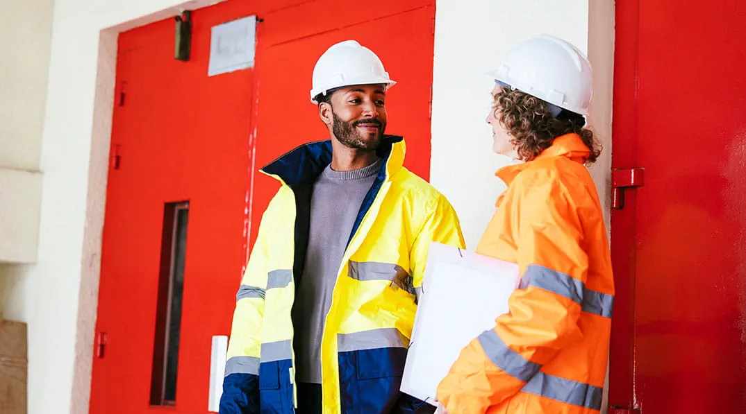 Twee collega's met bouwhelmen overleggen met elkaar