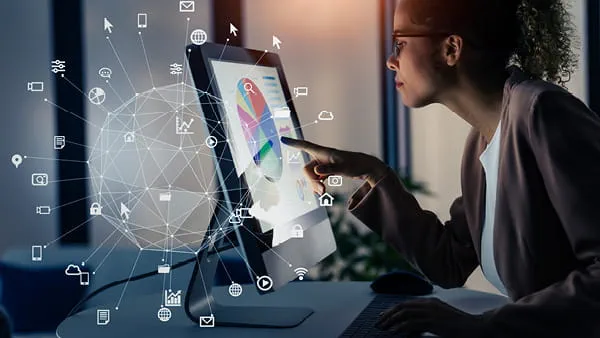 Person interacting with touchscreen displaying colorful data charts and tech icons