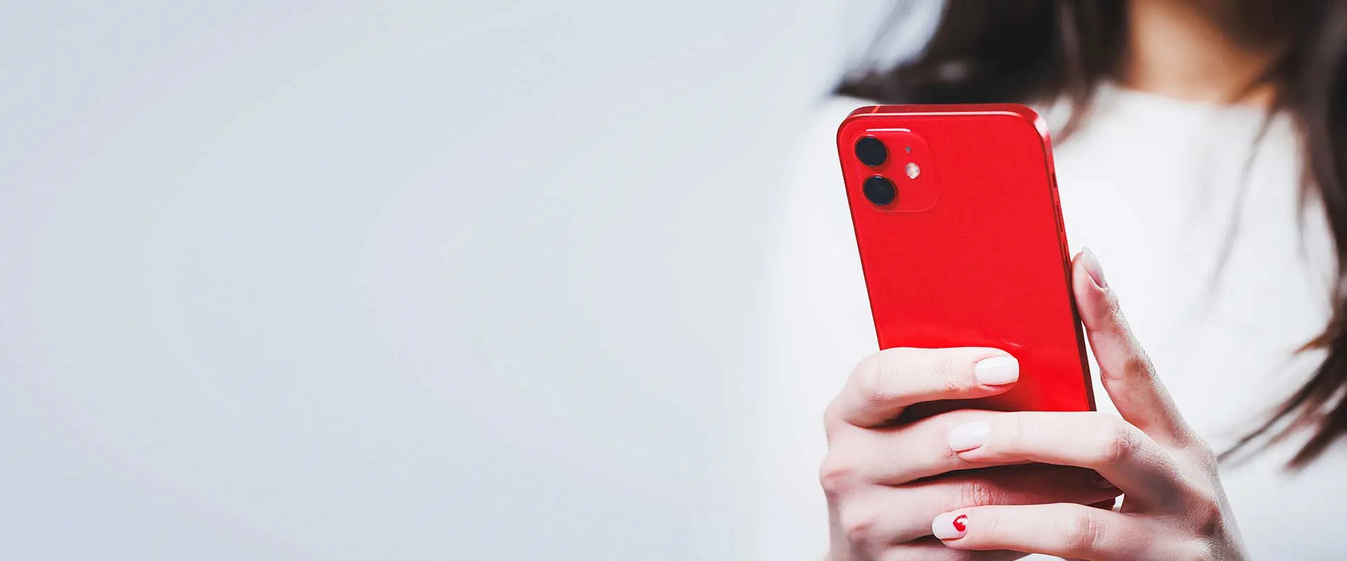 Person holding a red smartphone against a clean minimal background