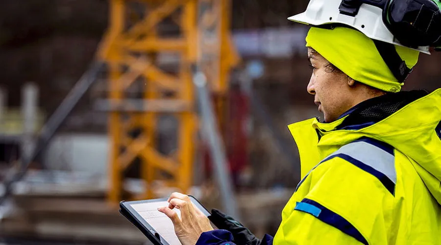 Engineer reviewing plans on tablet at construction site