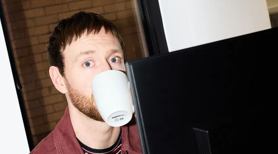 Man drinking coffee while working at computer