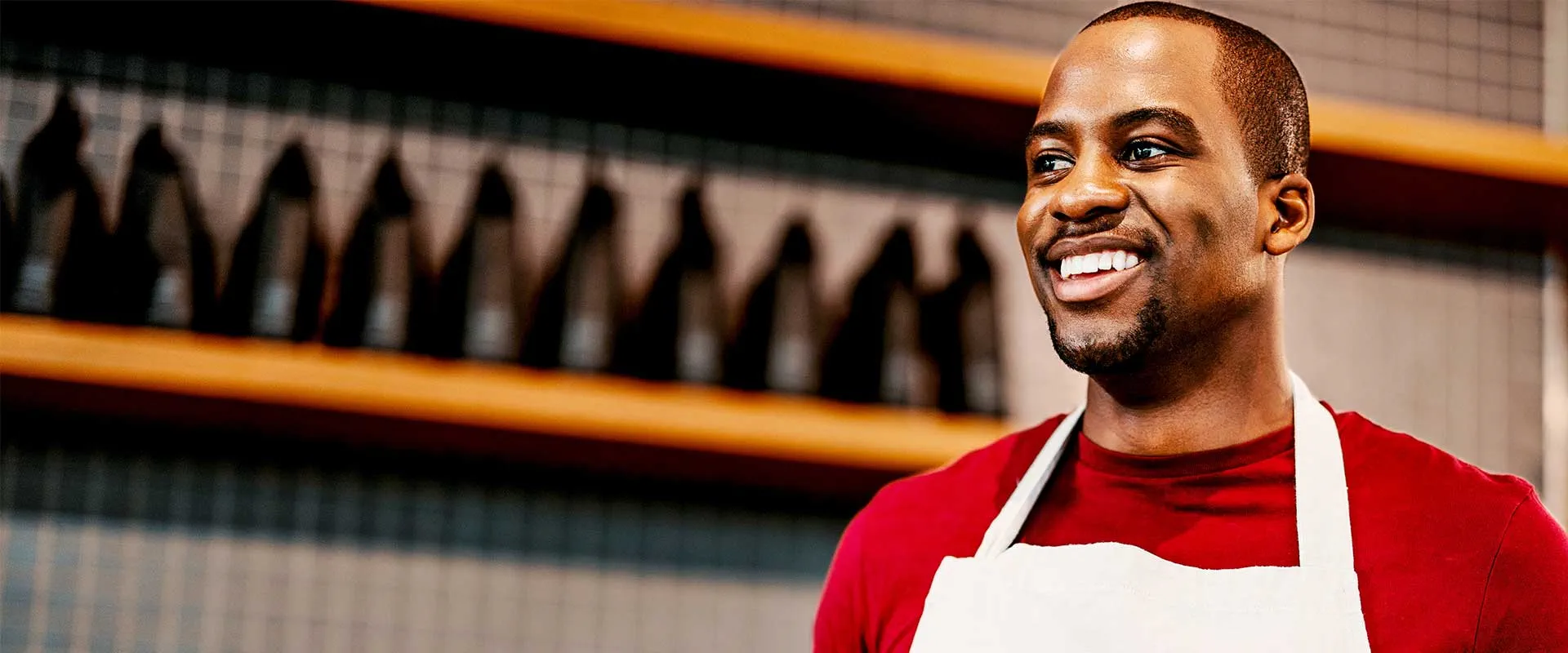 Smiling restaurant worker wearing apron in hospitality setting Smiling restaurant worker wearing apron in hospitality setting