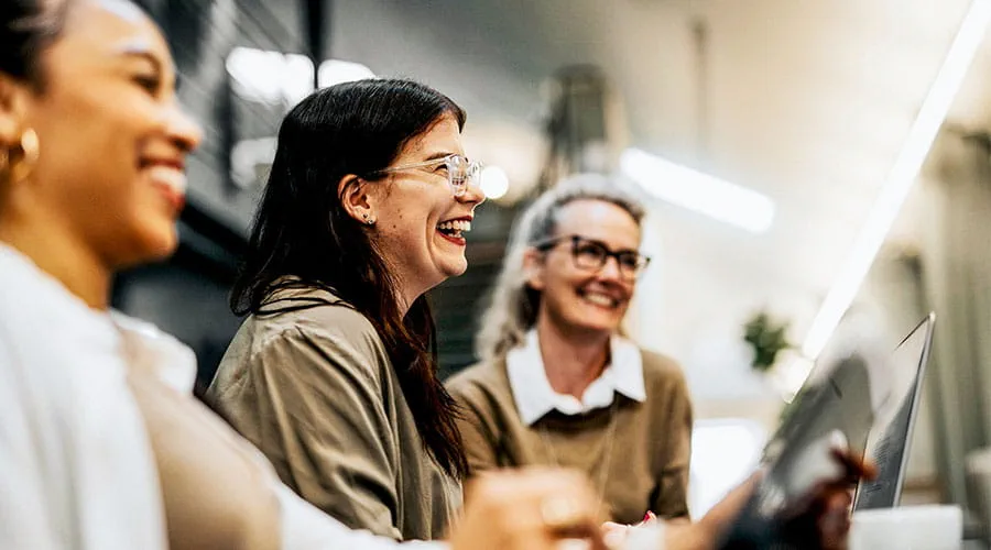 Group of colleagues laughing together in workplace Group of colleagues laughing together in workplace