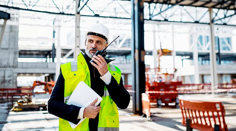 Site manager speaking on phone holding documents