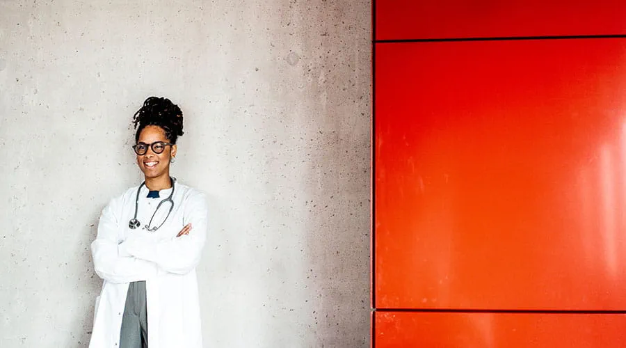 Médico de pie contra una pared con un detalle rojo