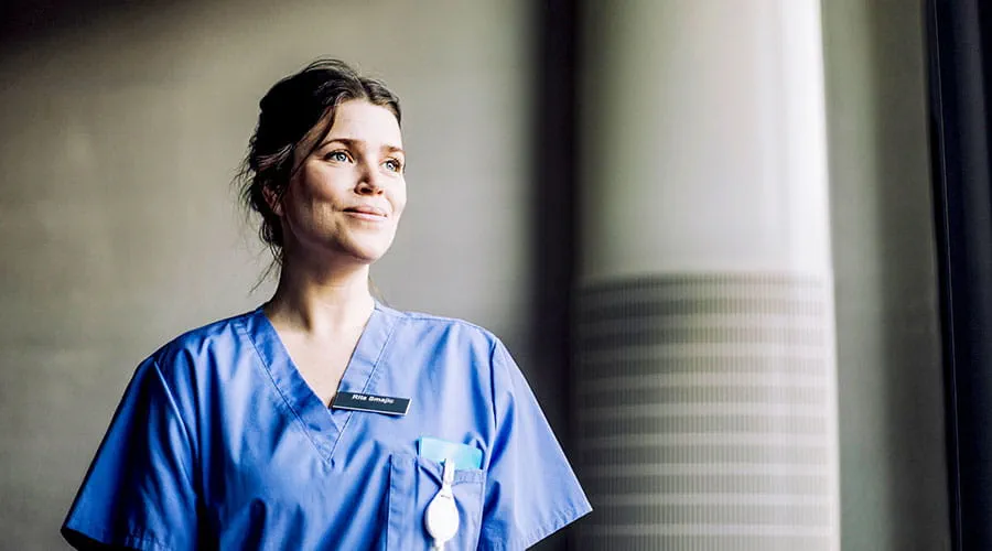 Nurse in scrubs standing near window