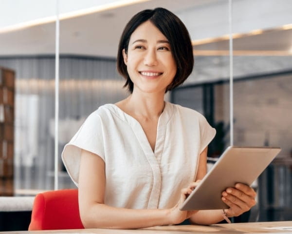 タブレットを持って笑顔で座る女性