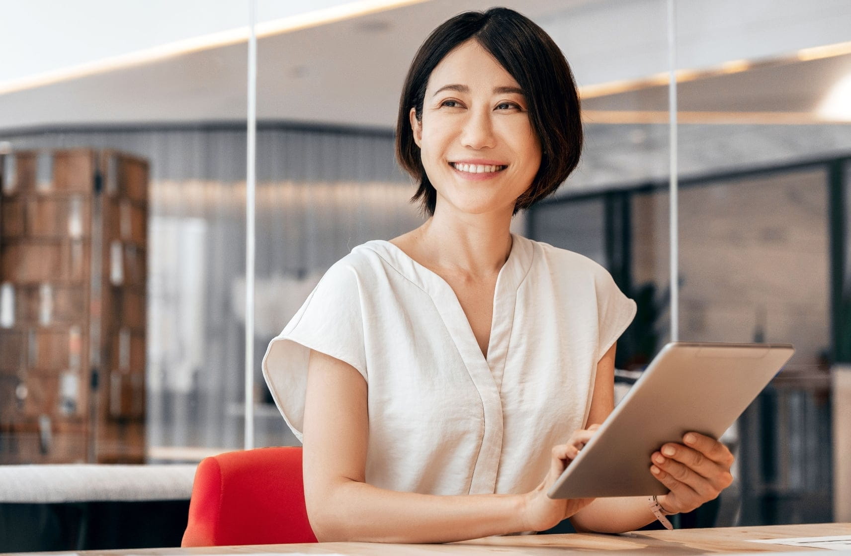 タブレットを持って笑顔で座る女性