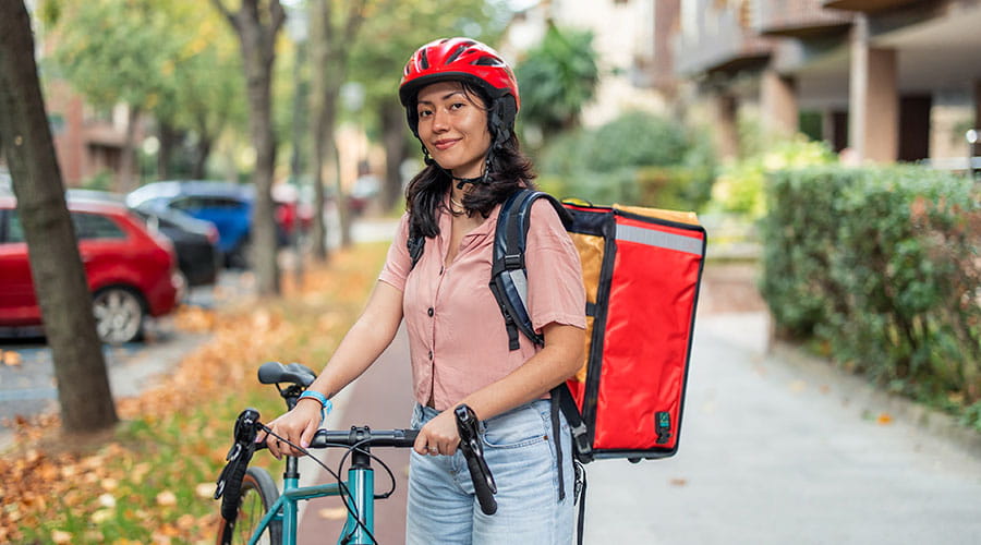 Repartidora montada en una bicicleta mirando a cámara