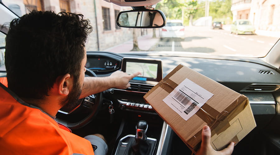Trabajador postal con paquetería en coche
