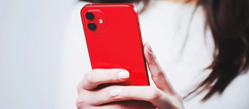 Des mains tenant un smartphone rouge