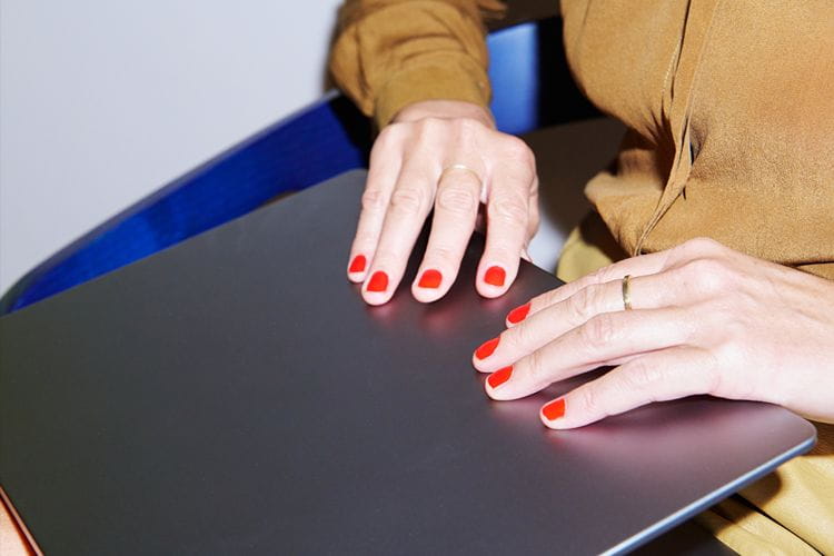 des mains avec du vernis rouge sur un ordinateur portable  