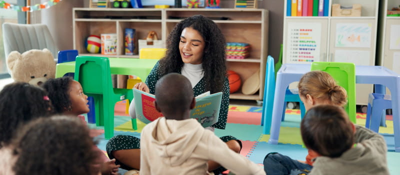 Une auxiliaire de puériculture lisant un livre à un groupe d'enfants dans une crèche Une auxiliaire de puériculture lisant un livre à un groupe d'enfants dans une crèche