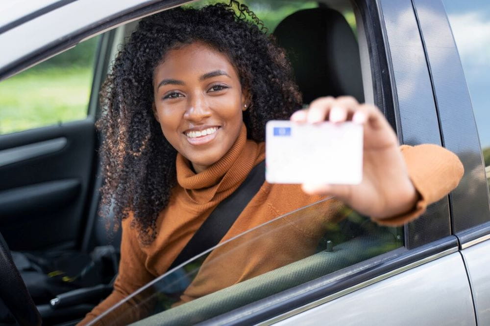 Femme heureuse au volant de sa voiture avec son permis de conduire
