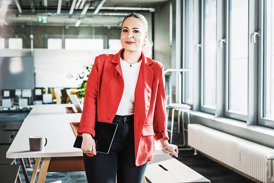 une salariée souriante avec une veste rouge et son ordinateur