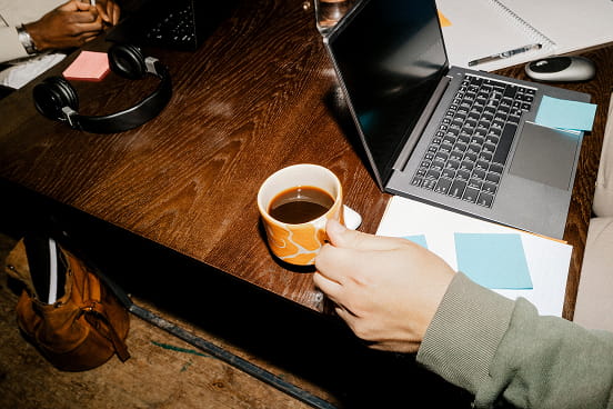 les mains d’un salarié à son ordinateur buvant un café