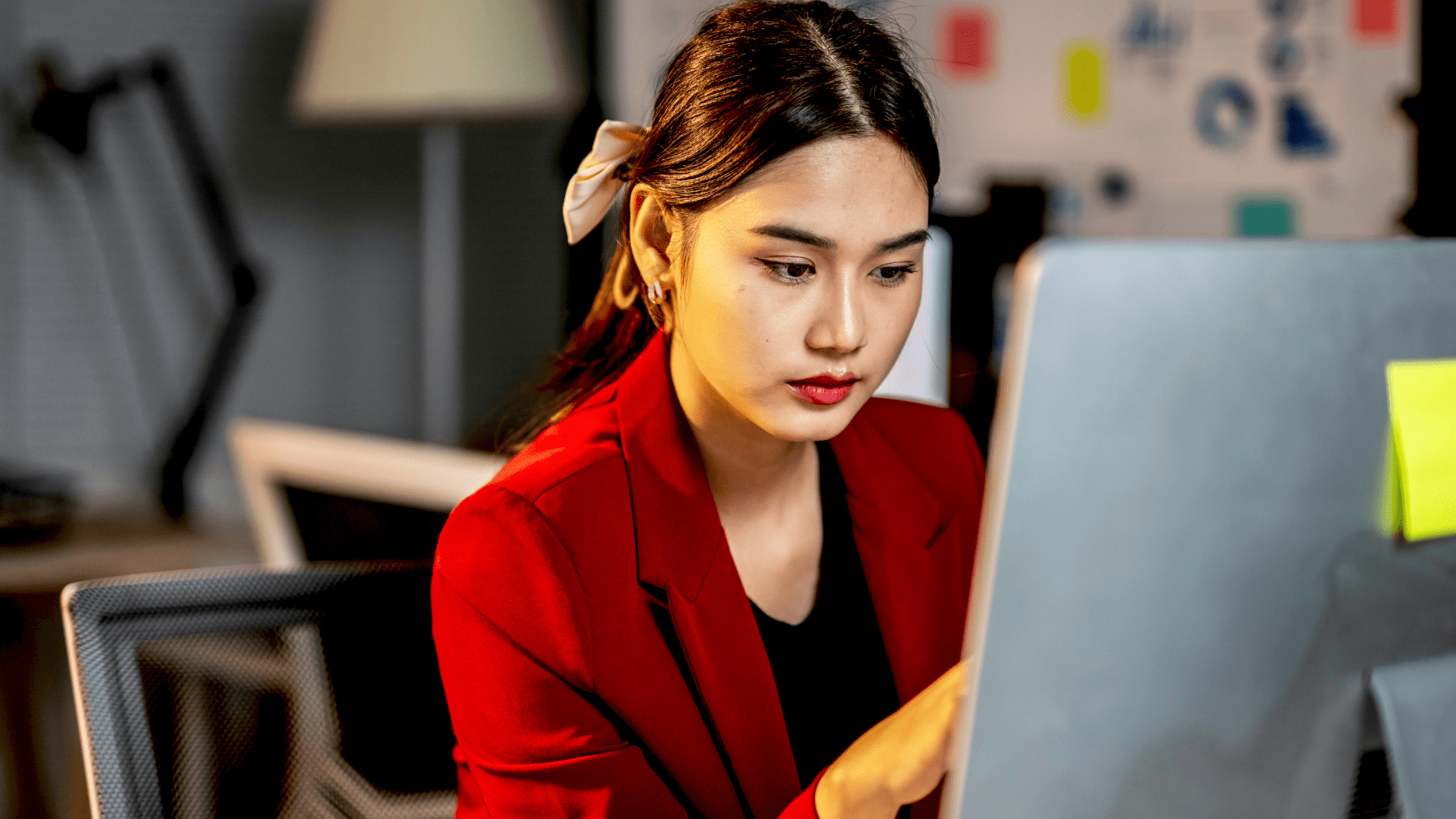 woman wearing a red blazer focusing on her computer screen woman wearing a red blazer focusing on her computer screen