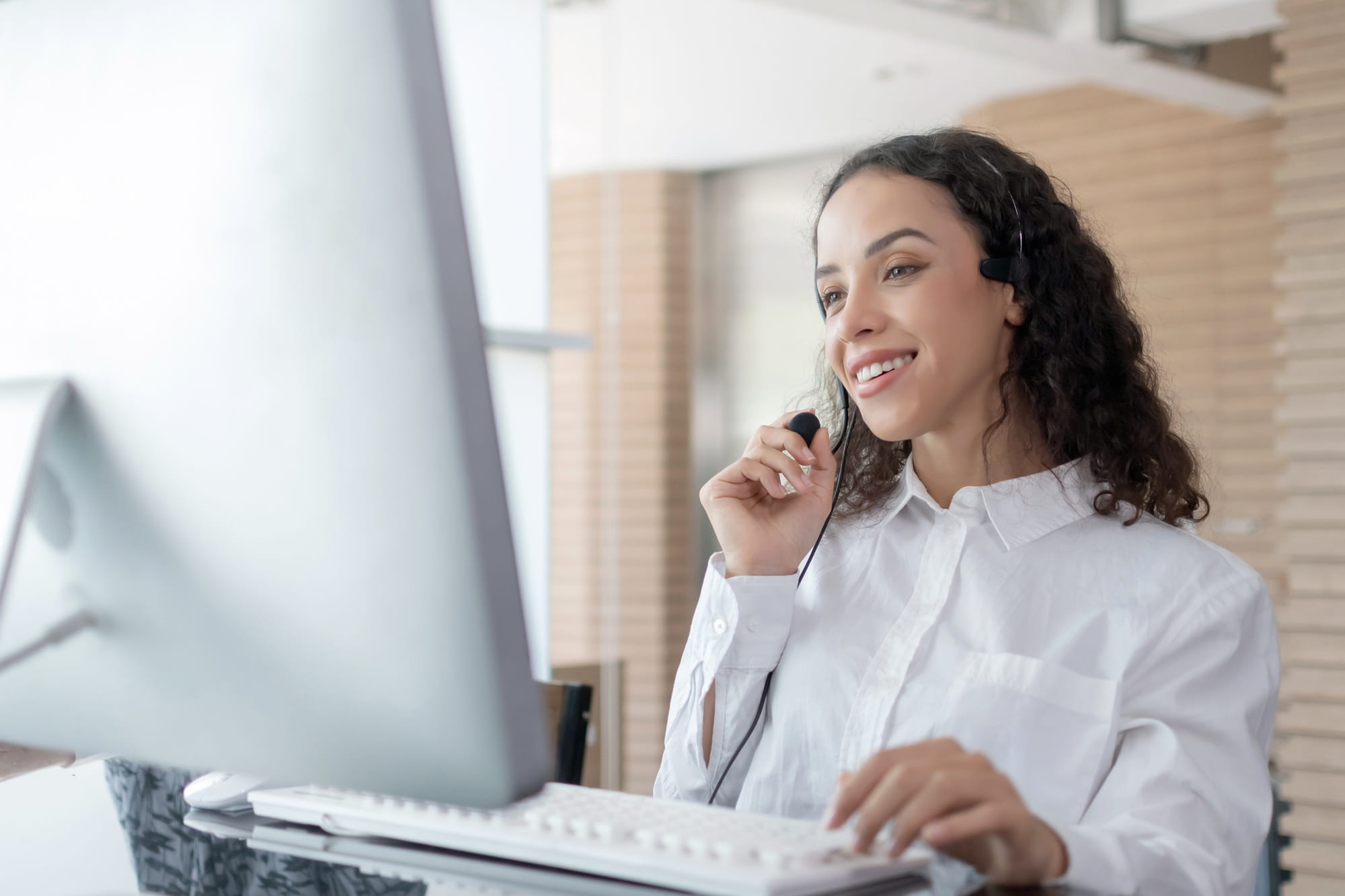 Una donna è seduta al computer e parla tramite un auricolare vivavoce. Una donna è seduta al computer e parla tramite un auricolare vivavoce.