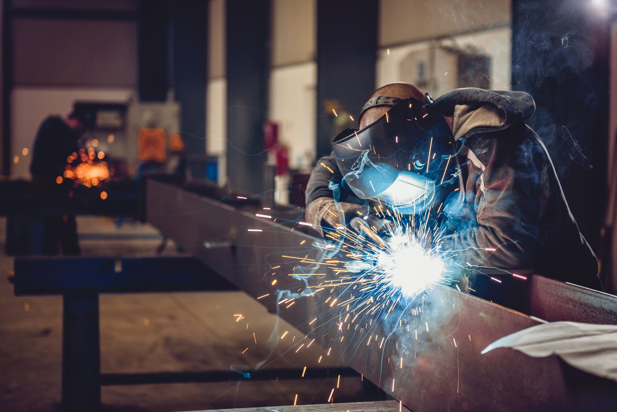 Un uomo sta saldando in uno stabilimento industriale.