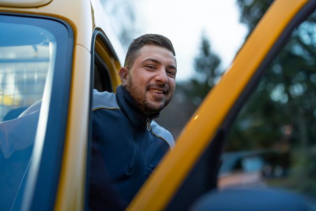 An employee steps out of a yellow delivery vehicle. An employee steps out of a yellow delivery vehicle.