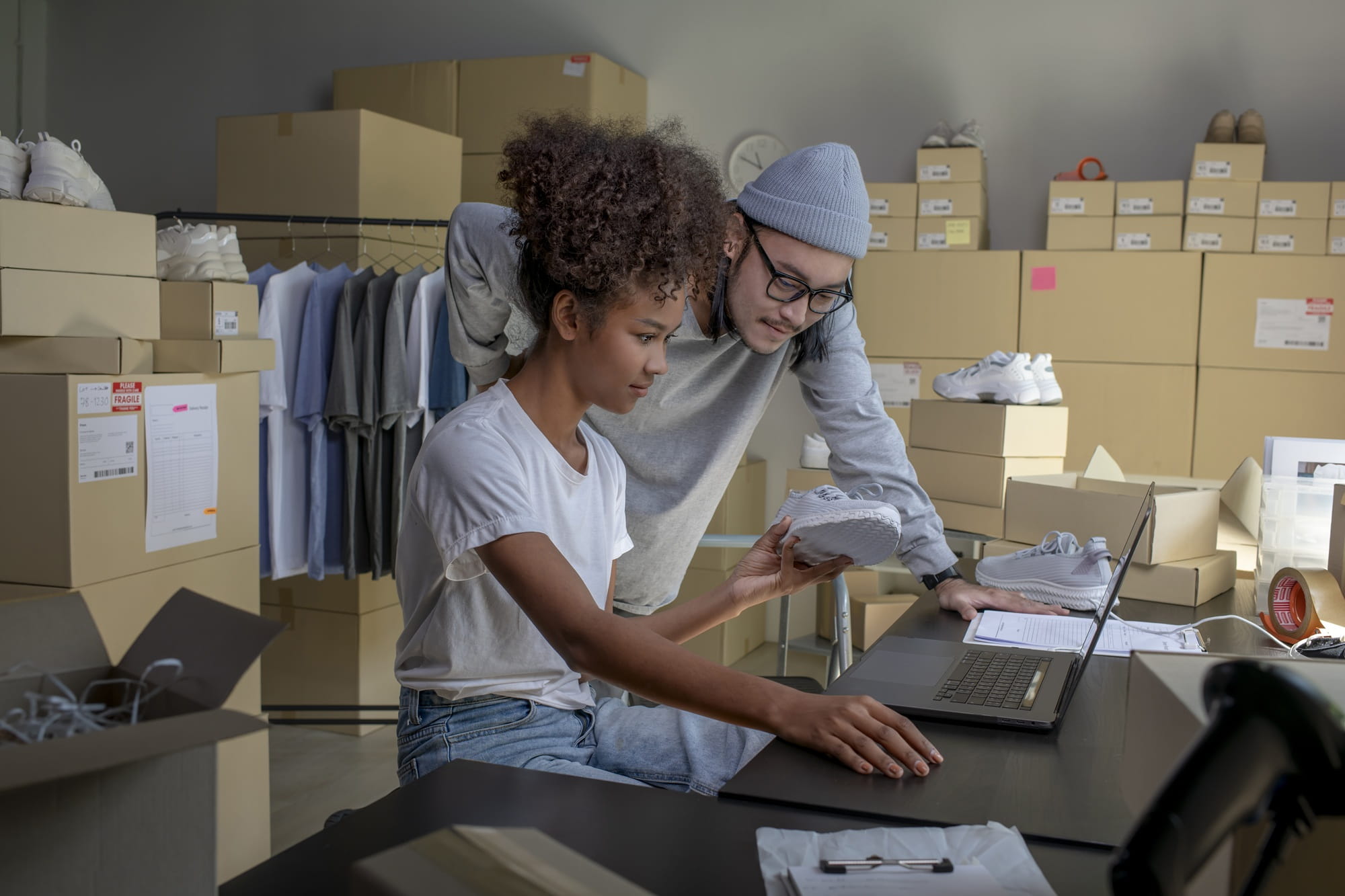 Two employees are working in a warehouse with shoes.