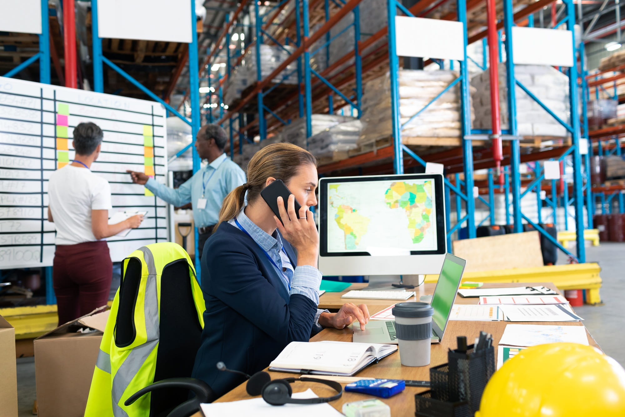 A woman is sitting with a laptop in a logistics warehouse. A woman is sitting with a laptop in a logistics warehouse.