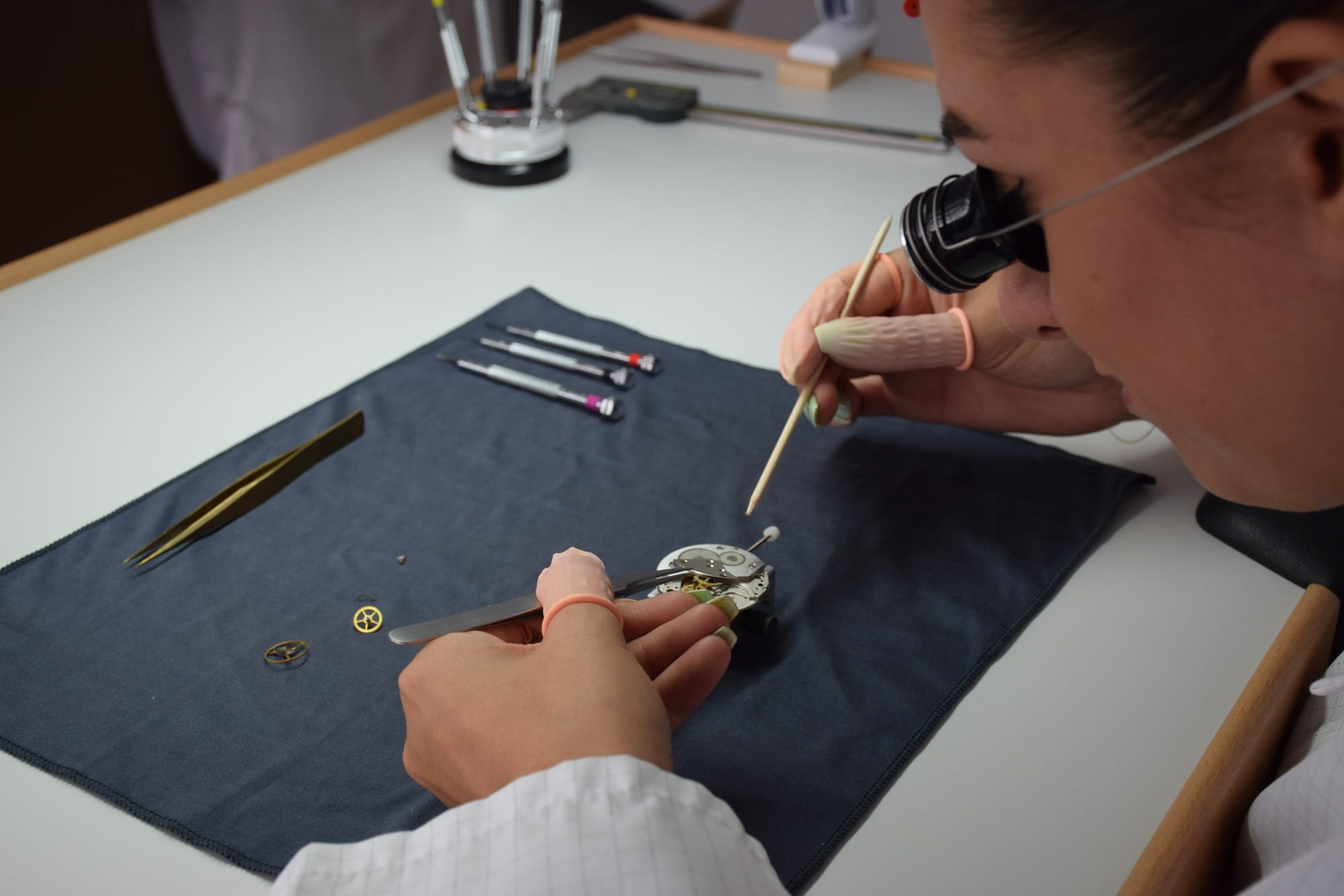 A watchmaker meticulously assembles a complex timepiece mechanism using precision tools in his workshop.