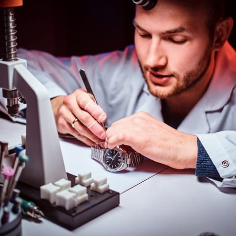A student of a watchmaking academy works attentively on a timepiece mechanism in a training workshop. A student of a watchmaking academy works attentively on a timepiece mechanism in a training workshop.