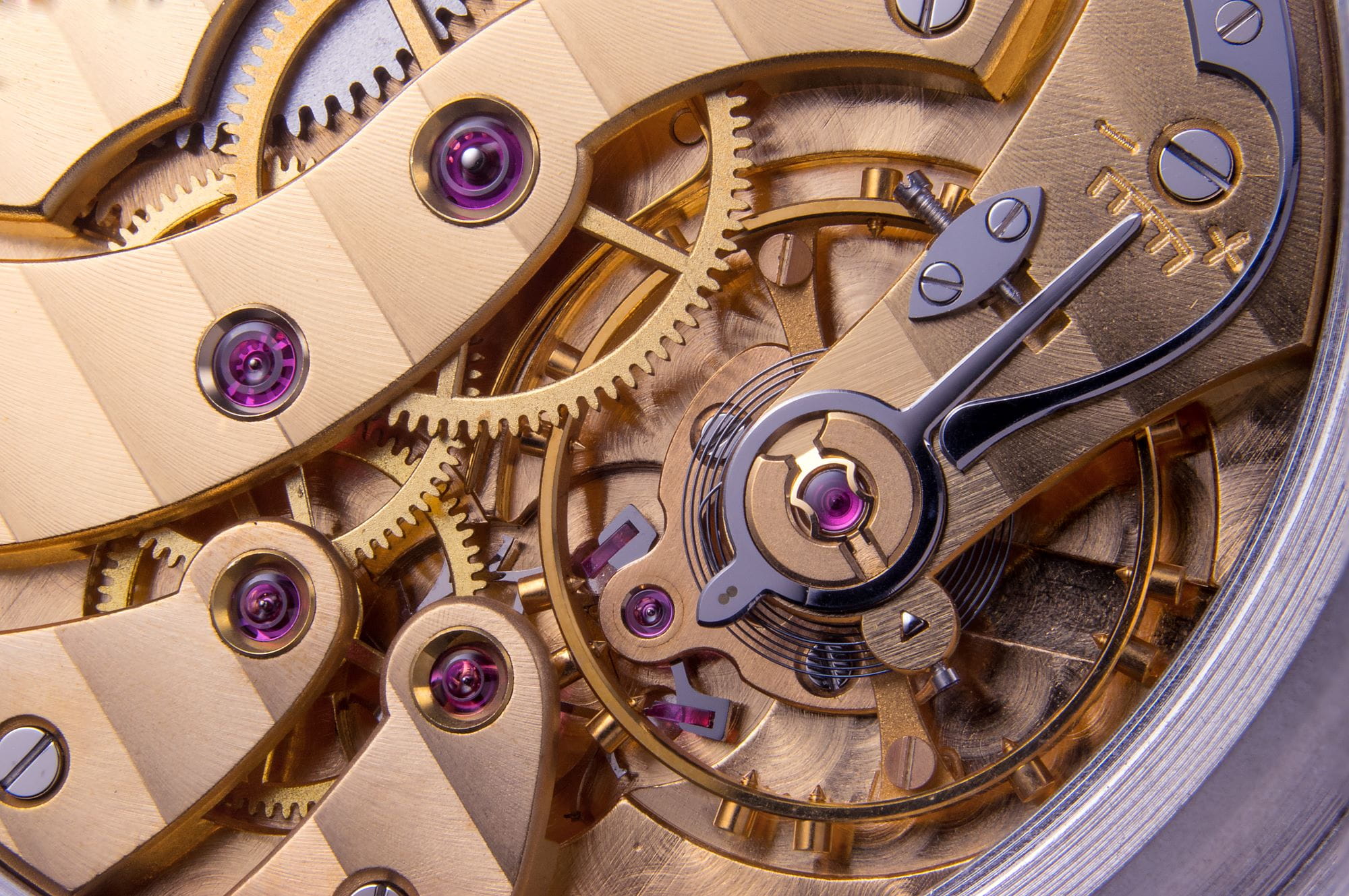 Photo macro d’un mécanisme de montre montrant des engrenages, des vis et des détails mécaniques fins.