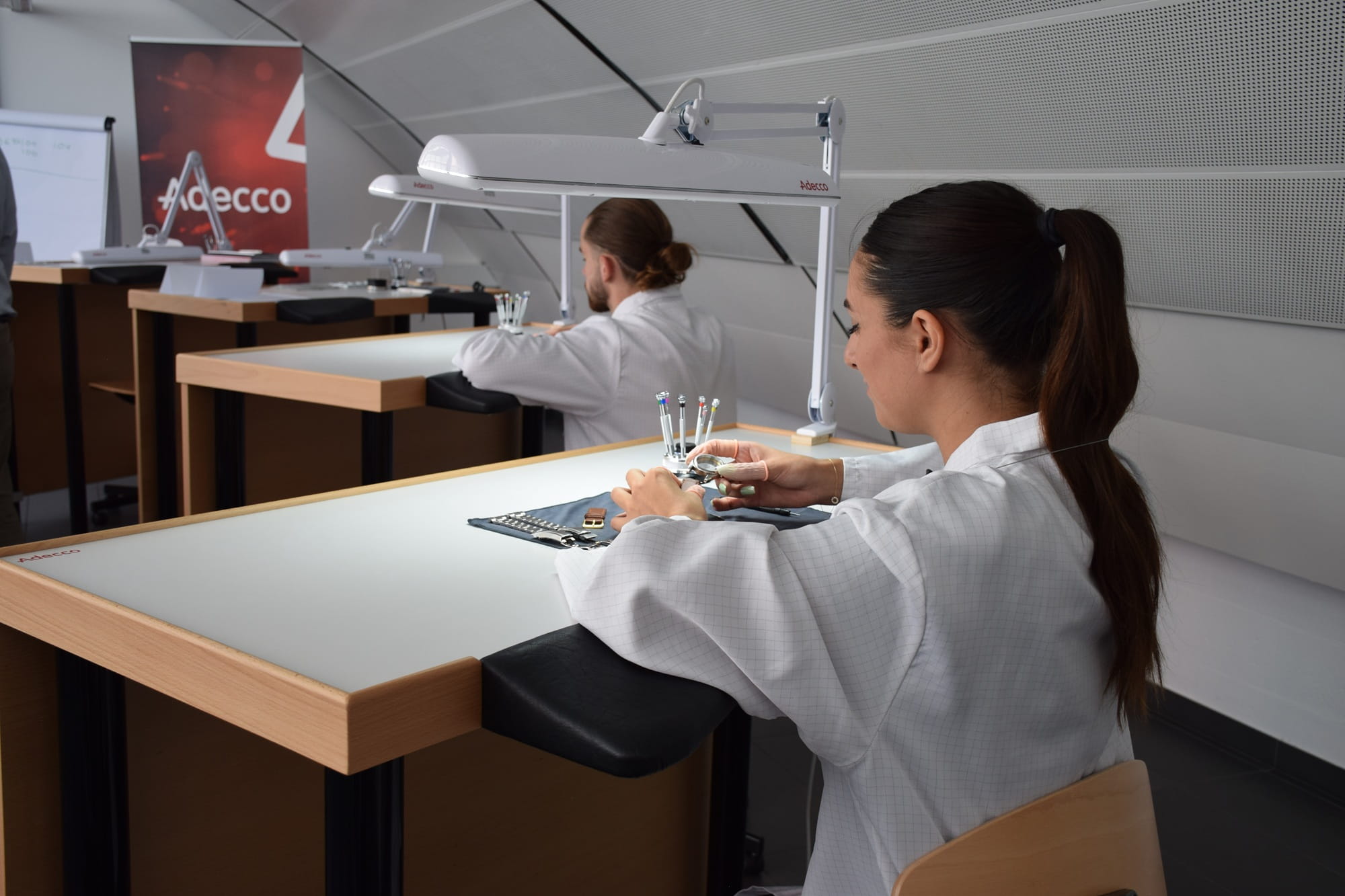 Studentesse di un'accademia di orologeria impegnate in attività pratiche con componenti di orologi e strumenti in un laboratorio didattico. Studentesse di un'accademia di orologeria impegnate in attività pratiche con componenti di orologi e strumenti in un laboratorio didattico.