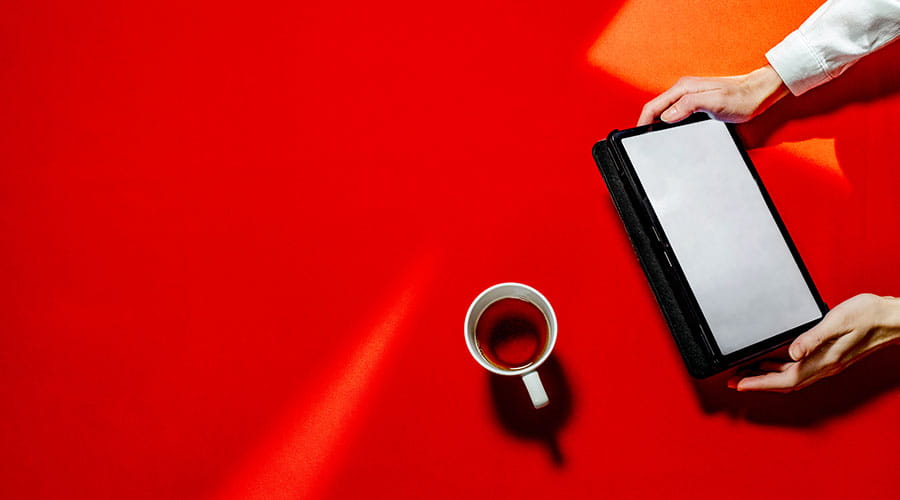 Tablet and coffee cup on red background
