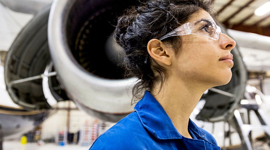 Technician inspecting aircraft engine in hangar